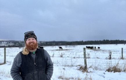 Farmer in winter with cattle in background. 