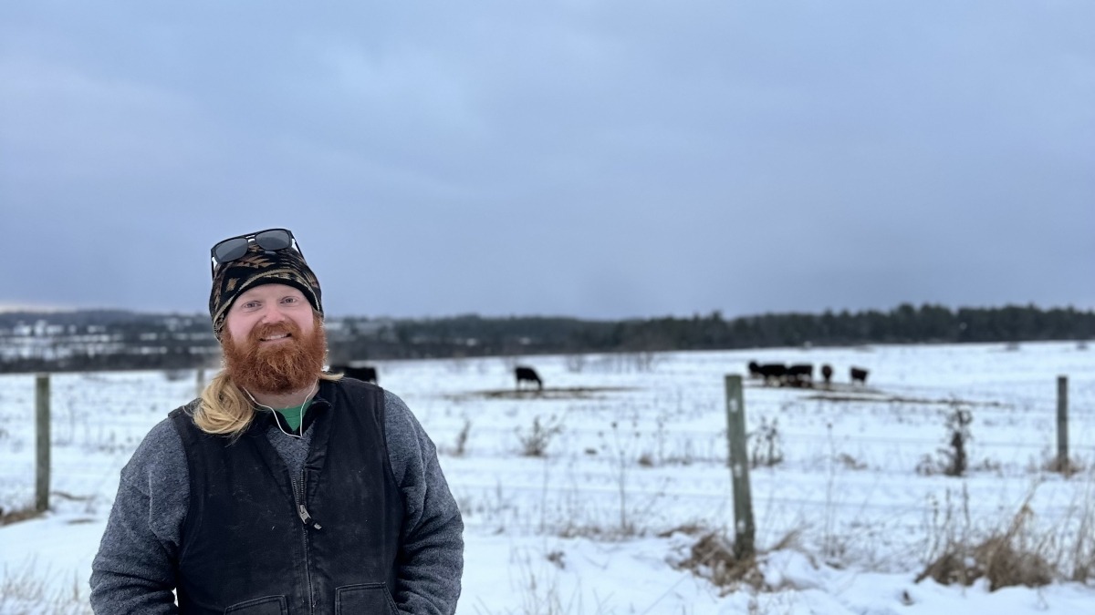 Farmer in winter with cattle in background. 