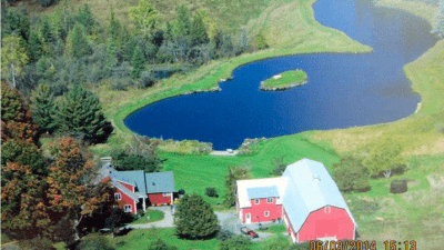 aerial view of farmhouse, dairy barn addition & pond